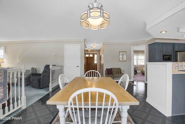 dining space with baseboards, dark floors, and wallpapered walls