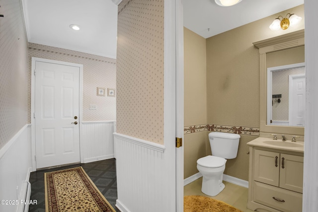 bathroom featuring a wainscoted wall, vanity, toilet, and wallpapered walls