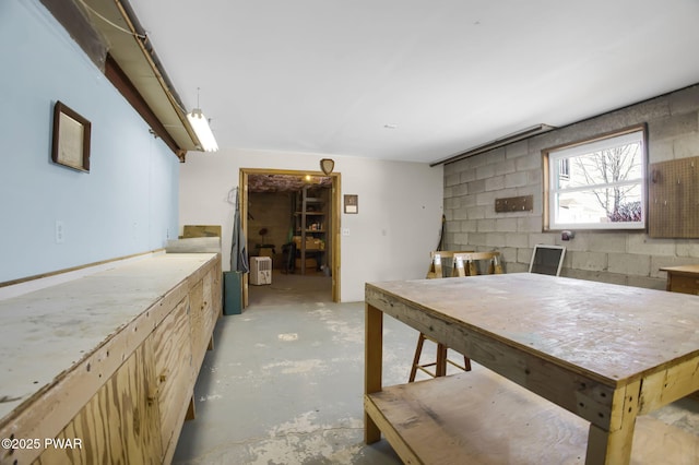 dining area with concrete block wall and unfinished concrete flooring