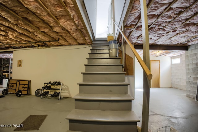 stairs featuring concrete flooring and concrete block wall