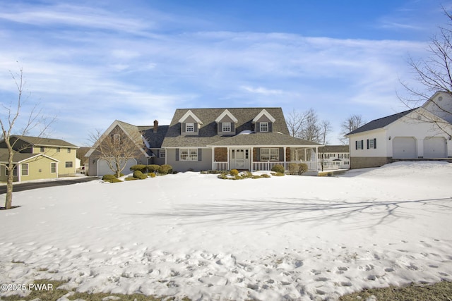 snow covered rear of property with a porch and a garage