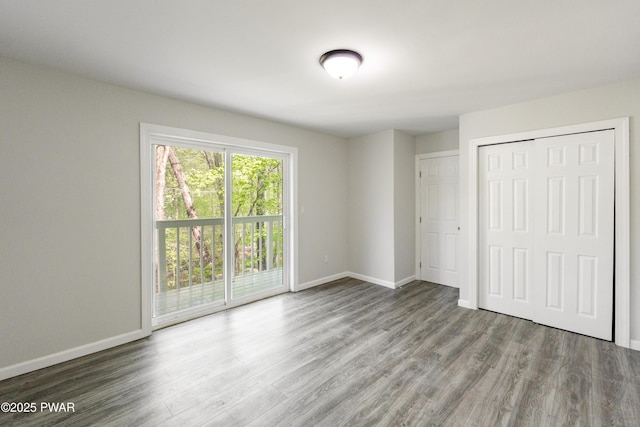 unfurnished bedroom featuring wood finished floors, access to outside, baseboards, and a closet