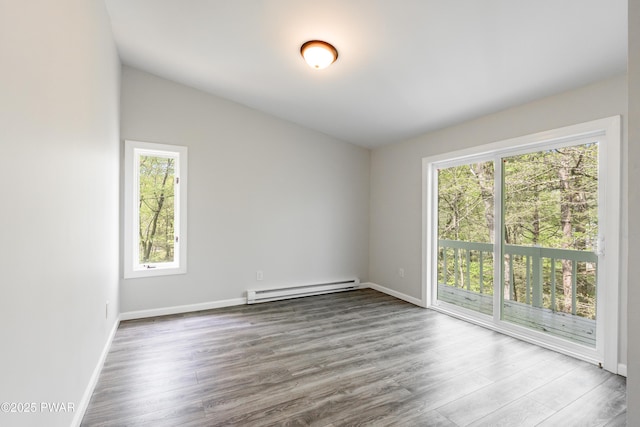 empty room with a baseboard radiator, wood finished floors, baseboards, and vaulted ceiling