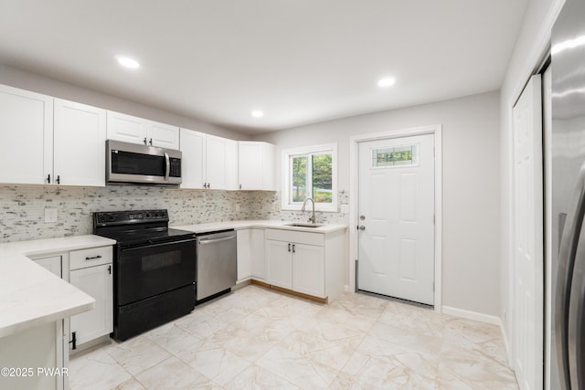 kitchen featuring appliances with stainless steel finishes, a sink, light marble finish flooring, backsplash, and light countertops
