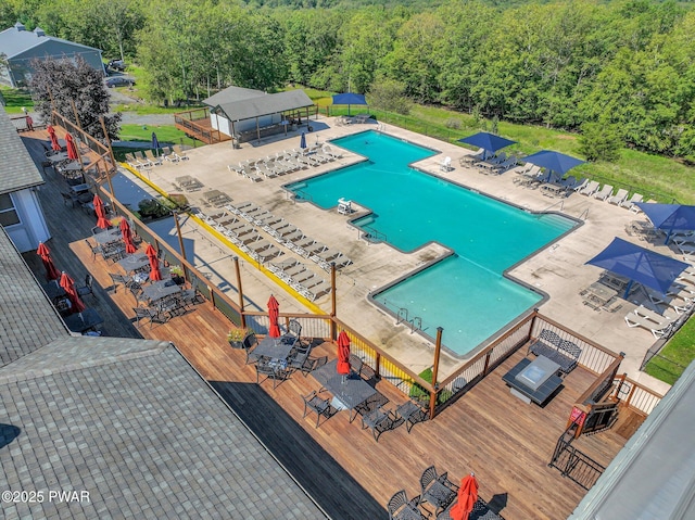 drone / aerial view of a pool and a heavily wooded area