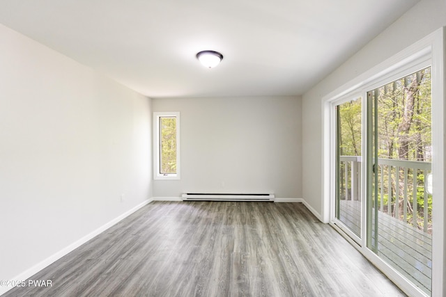 spare room with baseboards, wood finished floors, and baseboard heating