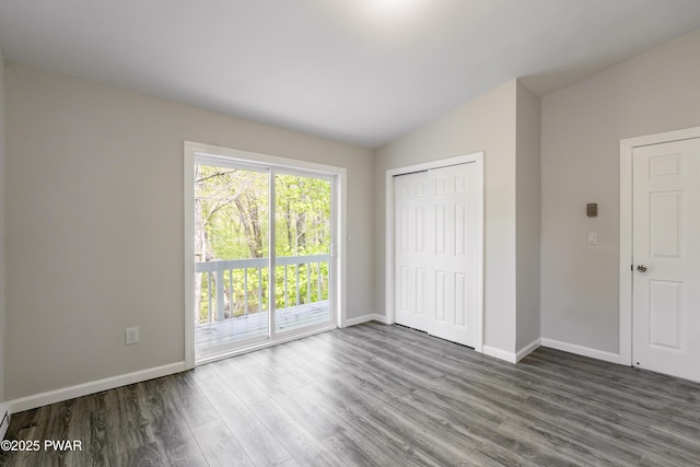 unfurnished bedroom featuring wood finished floors, lofted ceiling, access to exterior, baseboards, and a closet