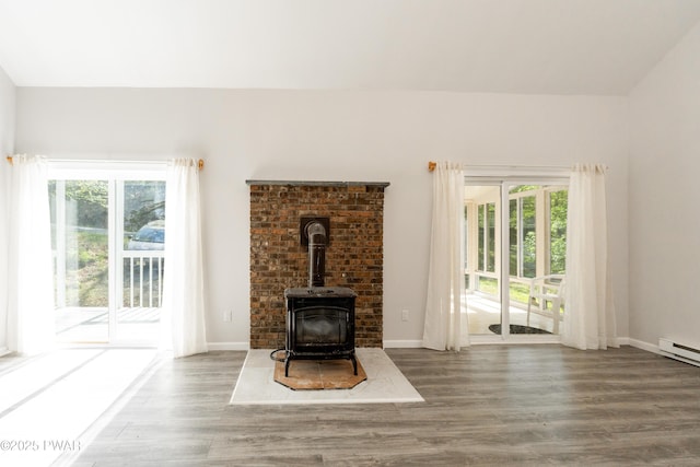 unfurnished living room with wood finished floors, healthy amount of natural light, and a wood stove