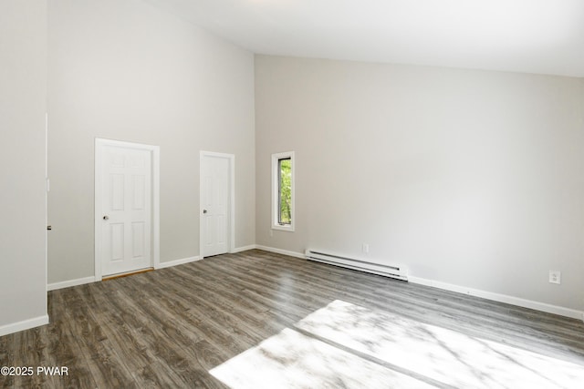 spare room with baseboard heating, high vaulted ceiling, wood finished floors, and baseboards