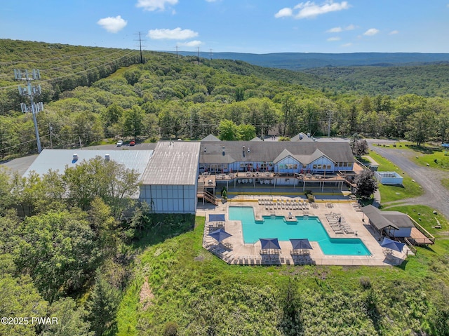 view from above of property featuring a heavily wooded area and a pool area