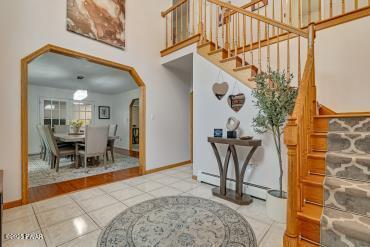 3043 Hemlock Rd, Stroudsburg, PA 18360 - foyer featuring arched walkways, a towering ceiling, tile patterned flooring, baseboards, and stairway
