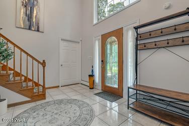 3043 Hemlock Rd, Stroudsburg, PA 18360 - foyer with tile patterned floors, stairs, a towering ceiling, and baseboards