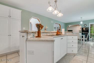 3043 Hemlock Rd, Stroudsburg, PA 18360 - kitchen featuring arched walkways, light tile patterned floors, a center island, white cabinets, and light countertops