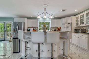 3043 Hemlock Rd, Stroudsburg, PA 18360 - kitchen featuring white oven, white cabinetry, a kitchen bar, glass insert cabinets, and recessed lighting