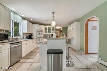 3043 Hemlock Rd, Stroudsburg, PA 18360 - kitchen featuring stainless steel appliances, a center island, a sink, light tile patterned flooring, and baseboard heating