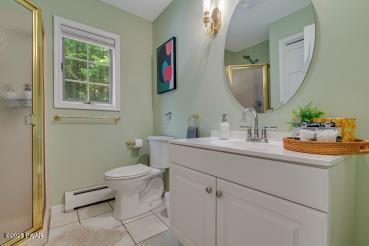 3043 Hemlock Rd, Stroudsburg, PA 18360 - bathroom with baseboard heating, vanity, a shower stall, toilet, and tile patterned flooring