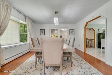 3043 Hemlock Rd, Stroudsburg, PA 18360 - dining area featuring a baseboard radiator, wood finished floors, and arched walkways