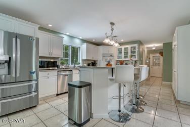 3043 Hemlock Rd, Stroudsburg, PA 18360 - kitchen with stainless steel appliances, light tile patterned floors, a breakfast bar area, a center island, and white cabinets