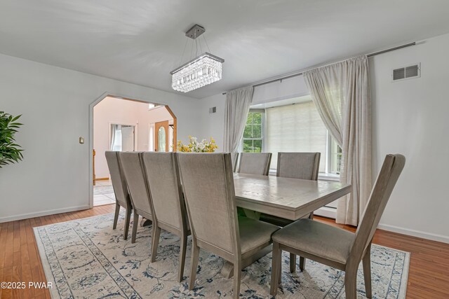 3043 Hemlock Rd, Stroudsburg, PA 18360 - dining space with baseboards, a chandelier, arched walkways, and light wood-style floors