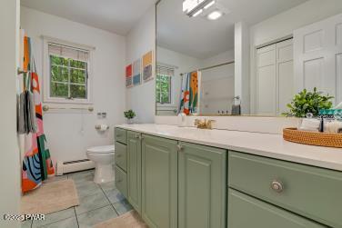 3043 Hemlock Rd, Stroudsburg, PA 18360 - bathroom with baseboard heating, vanity, toilet, tile patterned floors, and a shower with curtain