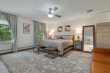 3043 Hemlock Rd, Stroudsburg, PA 18360 - bedroom featuring multiple windows, a ceiling fan, and a baseboard heating unit