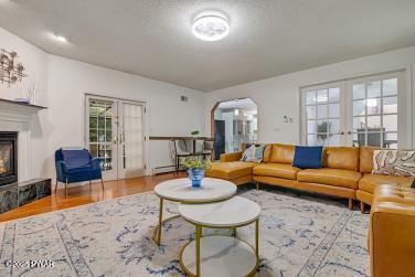 3043 Hemlock Rd, Stroudsburg, PA 18360 - living area with french doors, a glass covered fireplace, arched walkways, and wood finished floors