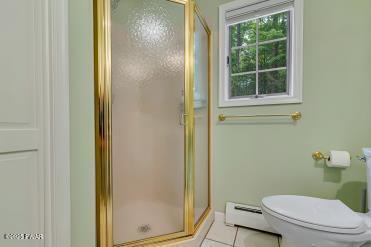 3043 Hemlock Rd, Stroudsburg, PA 18360 - full bathroom with toilet, a stall shower, a baseboard radiator, and tile patterned flooring