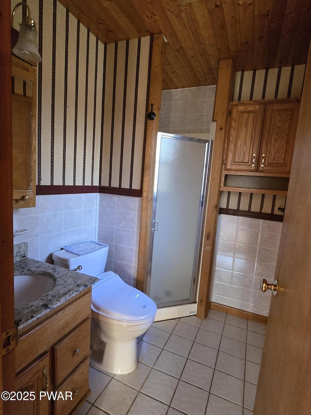 bathroom featuring tile patterned floors, tile walls, an enclosed shower, and vanity