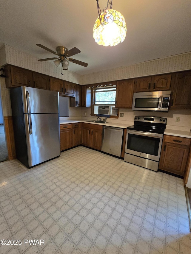 kitchen featuring ceiling fan, sink, hanging light fixtures, and stainless steel appliances