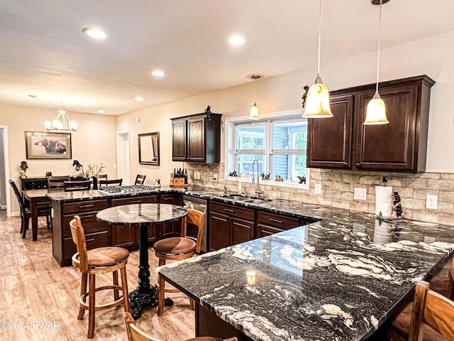 kitchen with pendant lighting, dark brown cabinetry, dark stone countertops, and sink