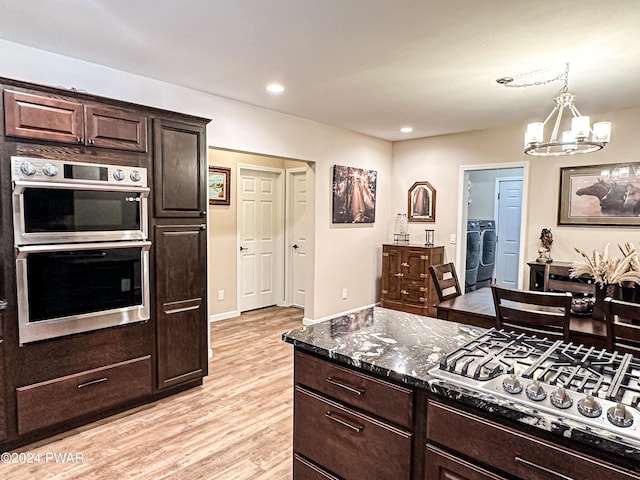 kitchen featuring dark stone countertops, independent washer and dryer, appliances with stainless steel finishes, a notable chandelier, and dark brown cabinetry