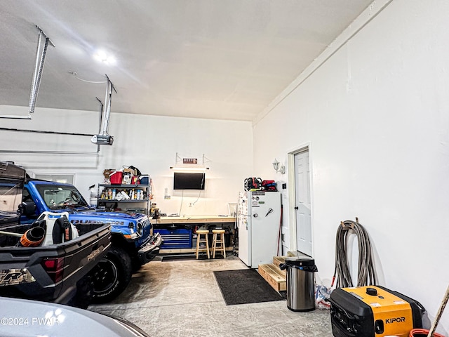 garage with white refrigerator, a garage door opener, and a workshop area