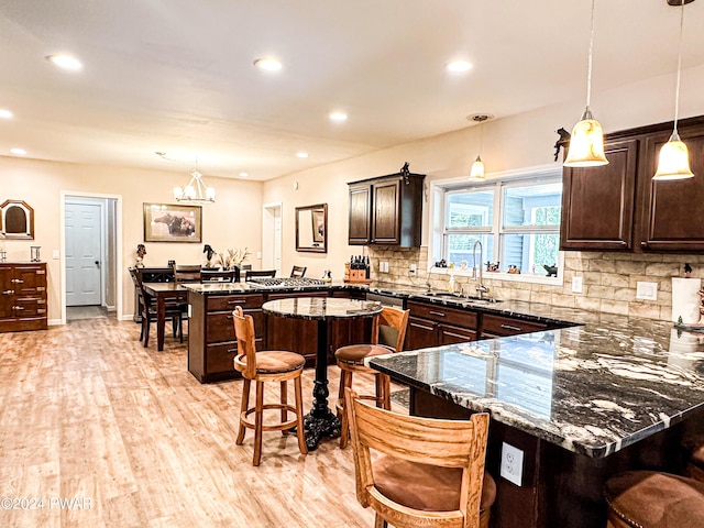 kitchen featuring pendant lighting, a kitchen breakfast bar, dark stone countertops, and sink