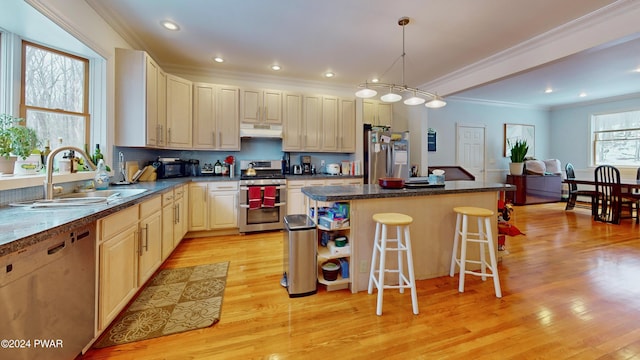 kitchen with a kitchen breakfast bar, sink, appliances with stainless steel finishes, decorative light fixtures, and a kitchen island