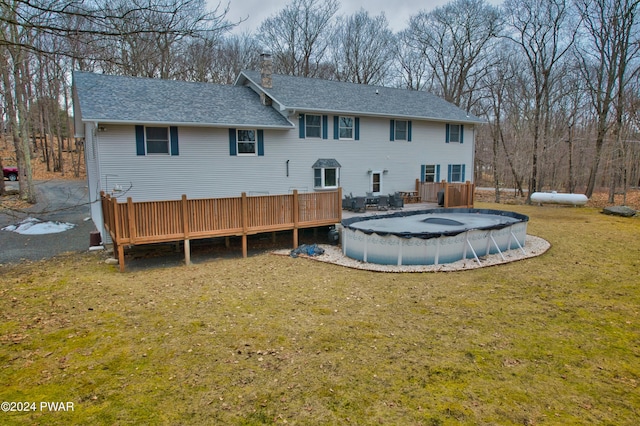 rear view of property featuring a lawn and a pool side deck