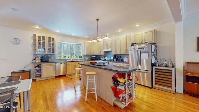 kitchen featuring appliances with stainless steel finishes, a breakfast bar, a kitchen island, decorative light fixtures, and wine cooler