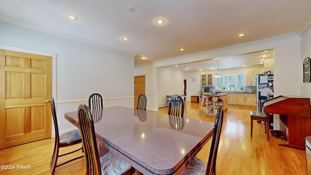 dining room with crown molding and light hardwood / wood-style floors