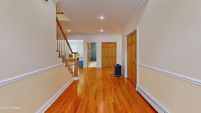 corridor featuring light wood-type flooring, crown molding, and a baseboard radiator