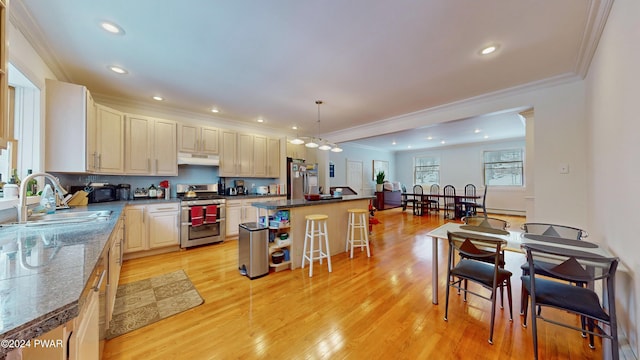 kitchen featuring sink, pendant lighting, a breakfast bar, a kitchen island, and appliances with stainless steel finishes