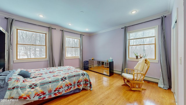 bedroom with light wood-type flooring, crown molding, and a baseboard heating unit