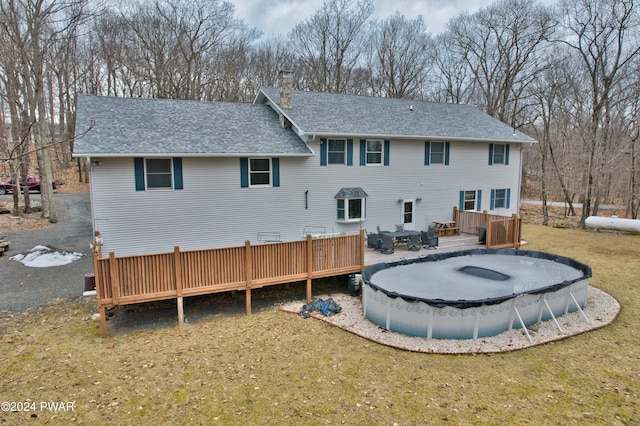 rear view of property featuring a yard and a pool side deck