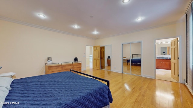 bedroom with ensuite bath, crown molding, light hardwood / wood-style flooring, and multiple closets