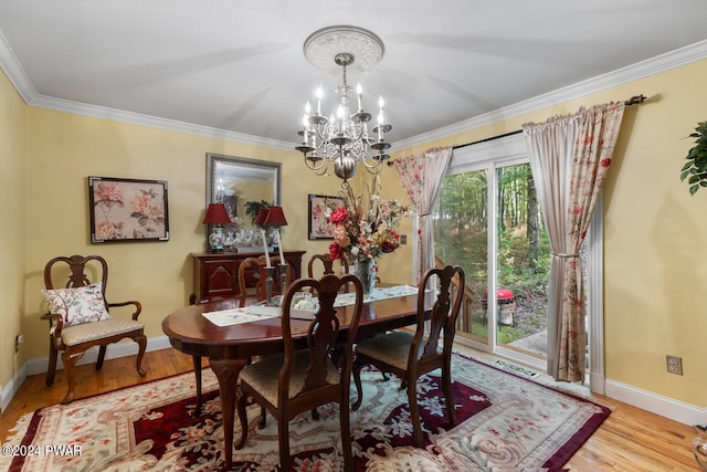 dining area with crown molding, an inviting chandelier, and light wood-type flooring