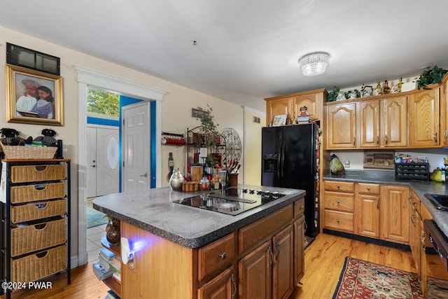 kitchen with light wood-type flooring, a kitchen island, and black appliances