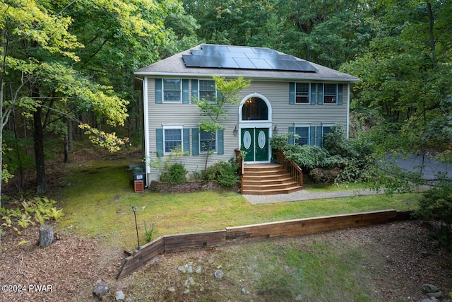 colonial-style house featuring a front lawn and solar panels