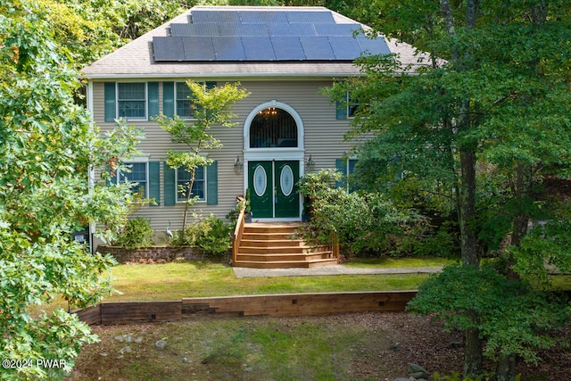 view of front of property featuring solar panels and a front yard