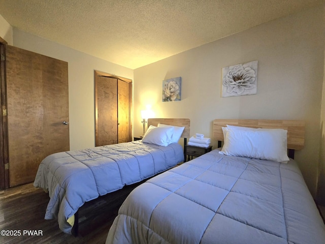 bedroom with a textured ceiling, a closet, and dark hardwood / wood-style flooring