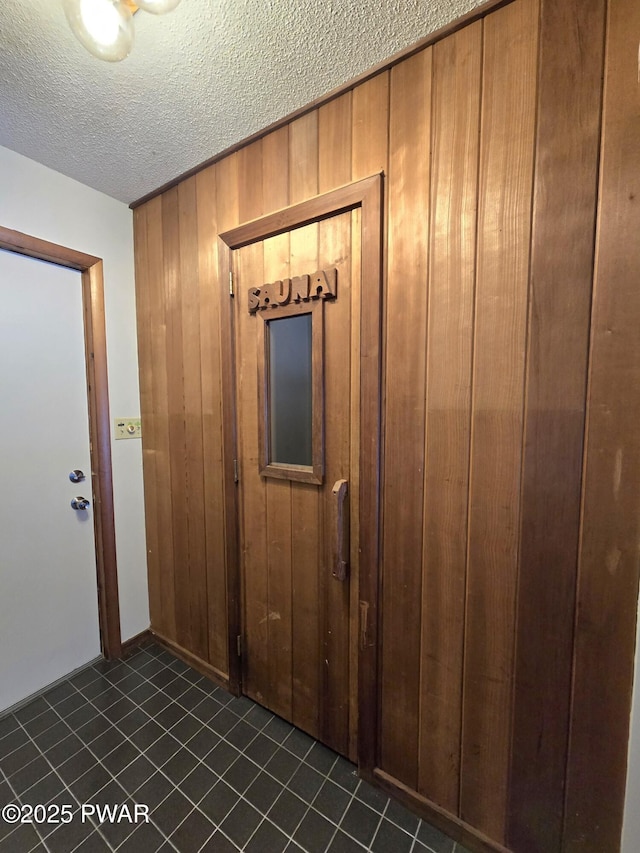 hall featuring wood walls and a textured ceiling