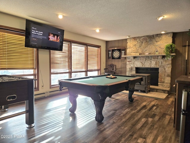 game room with dark wood-type flooring, a textured ceiling, pool table, and a stone fireplace