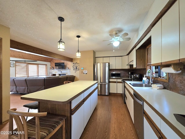 kitchen with white cabinetry, hanging light fixtures, sink, backsplash, and stainless steel appliances